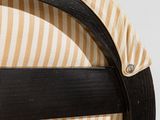 the back of a black and tan striped chair with a wooden frame