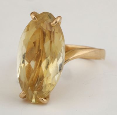 Gros plan sur une bague en or jaune sertie d'une citrine de taille ovale