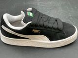 black and white puma sued sneakers with a green and white logo on the side