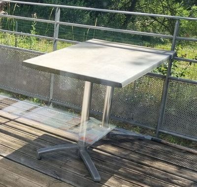 une petite table sur une terrasse en bois, avec une clôture en arrière-plan