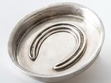 a silver bowl with a horseshoe on it on a white surface