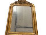 un miroir avec un cadre doré sur un mur blanc
