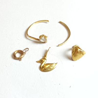 trois bijoux en or posés sur une surface blanche