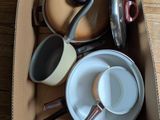 de nombreuses casseroles et poêles dans une boîte posée sur une table