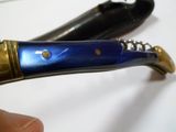 quelqu'un tient un couteau avec un manche bleu et un manche doré