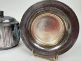 a silver plate with a lid next to a silver pot