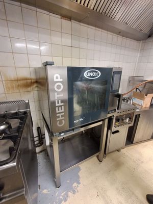 un homme debout dans une cuisine, à côté d'un four