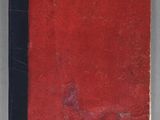 an old book with a red cover sitting on top of a table