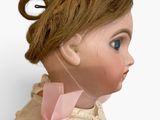 a close up of a doll with a pink bow on it ' s head