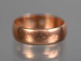 a close up of a gold wedding ring on a reflective surface