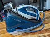 a blue and white steam iron sitting on a wooden table