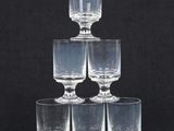 six clear wine glasses stacked on top of each other on a black background