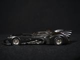 a toy batmobile that is sitting on a black surface