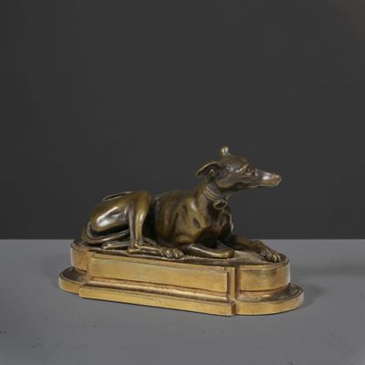 a bronze statue of a dog laying on a book