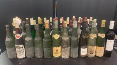 Des bouteilles de vin sont alignées sur une table devant un mur noir