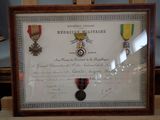 a framed picture of medals and a certificate on display