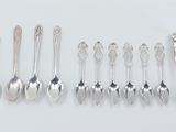 six silver spoons and two silver spoons on a white surface