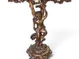 an antique bronze table with a cupid on it and a marble top
