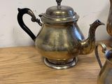 two silver teapots sitting on a wooden table