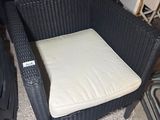 une chaise en osier avec un coussin posé dessus, dans une pièce