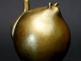 un vase doré orné d'un chat sur un fond noir