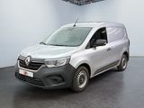 La camionnette argentée est garée dans une pièce blanche au sol noir.