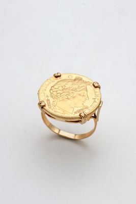 a gold ring with a coin on top of it