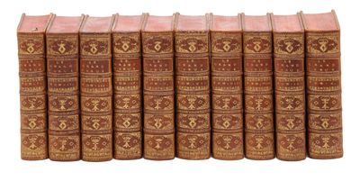 six vieux livres sont alignés en rangées sur une surface blanche