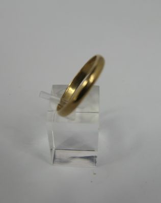 a close up of a gold wedding ring on a clear stand