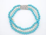un bracelet en perles blanches et bleues avec un fermoir en argent