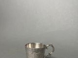 an antique silver cup with a handle on a gray background