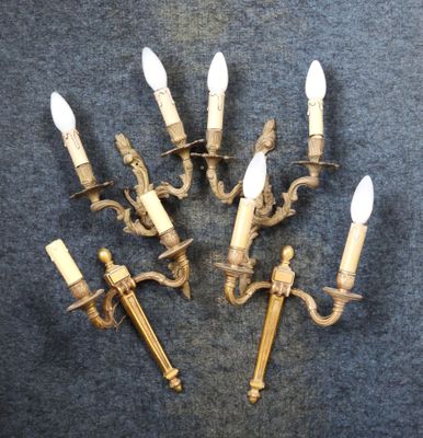 six antique brass wall sconces with white candles on a blue background