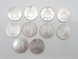 six types différents de pièces d'argent sur une surface blanche