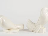 pair of white ceramic birds on stands on a white background