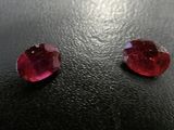 a pair of red sapphires sitting on top of a black surface