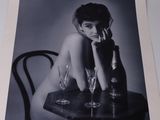 black and white photograph of a woman sitting at a table with wine glasses