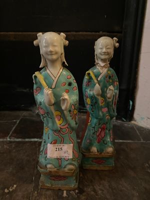 two asian figurines sitting on a stone floor