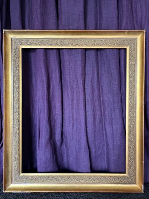 an empty picture frame sitting on top of a purple curtain