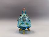 une petite bouteille en verre bleue ornée d'un oiseau