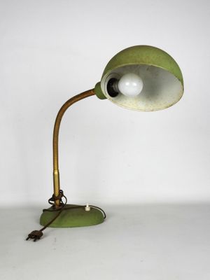 une image représentant une lampe verte posée sur une table, sur fond blanc