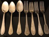 six spoons and six forks sitting on a table