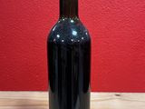 a bottle of wine sitting on a table with a red wall in the background