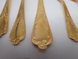 five spoons and a fork on a white table