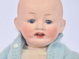 a baby doll wearing a blue sweater and a white shirt