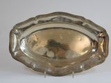 a silver plate on a stand on a white surface