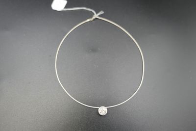 un collier en argent orné d'une perle blanche sur un fond noir