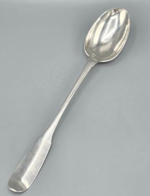 cuillère plaquée argent avec un long manche, posée sur une surface grise