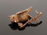 an image of a gold bird broochle sitting on a black surface