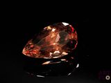 a close up of a large orange diamond on a black surface