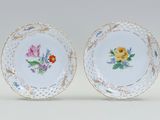 pair of porcelain plates with floral designs on them on a white surface
